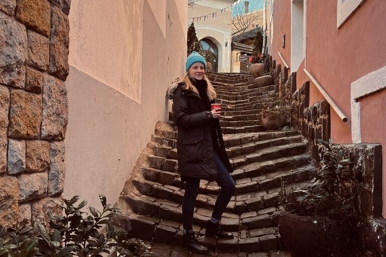 A girl standing on stairs around buildings near Budapest, Hungary.