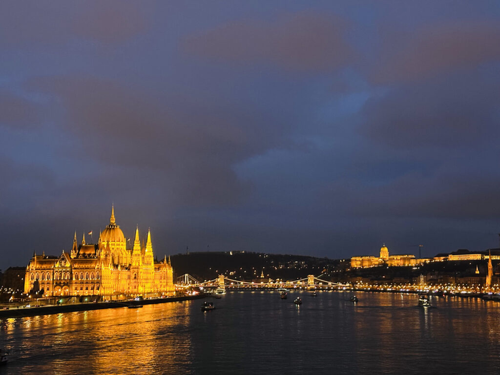 Boats on the River Danube at night in Budapest with the Parliament lit up in the background.